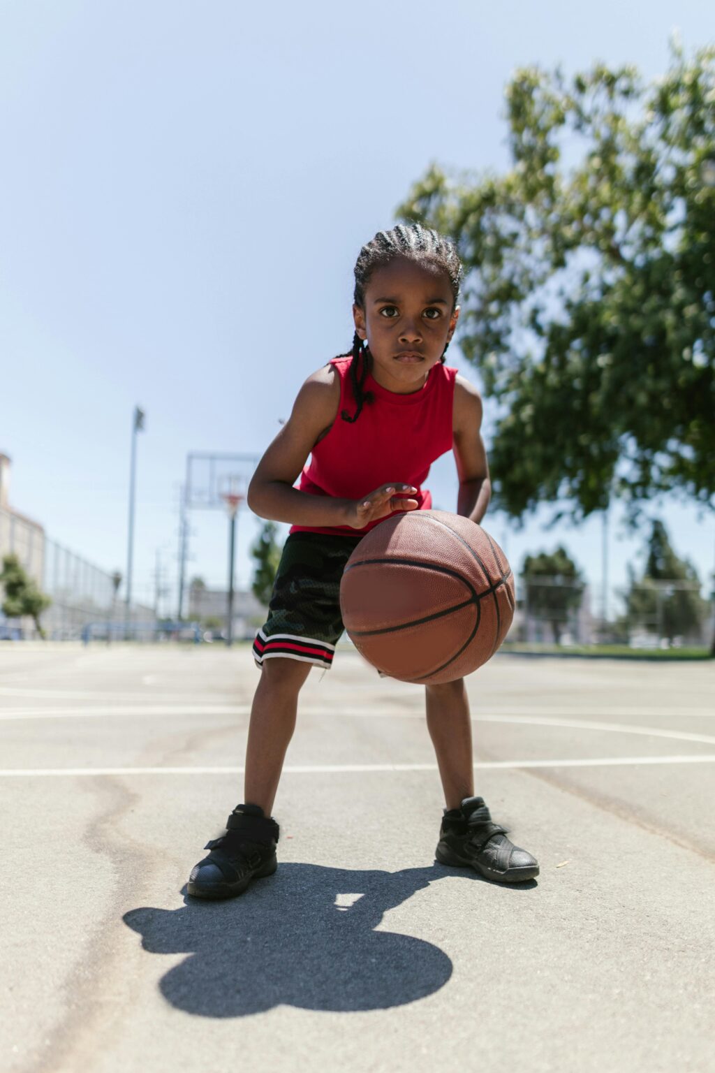 Energetic child playing basketball on a sunny outdoor court, showcasing determination.